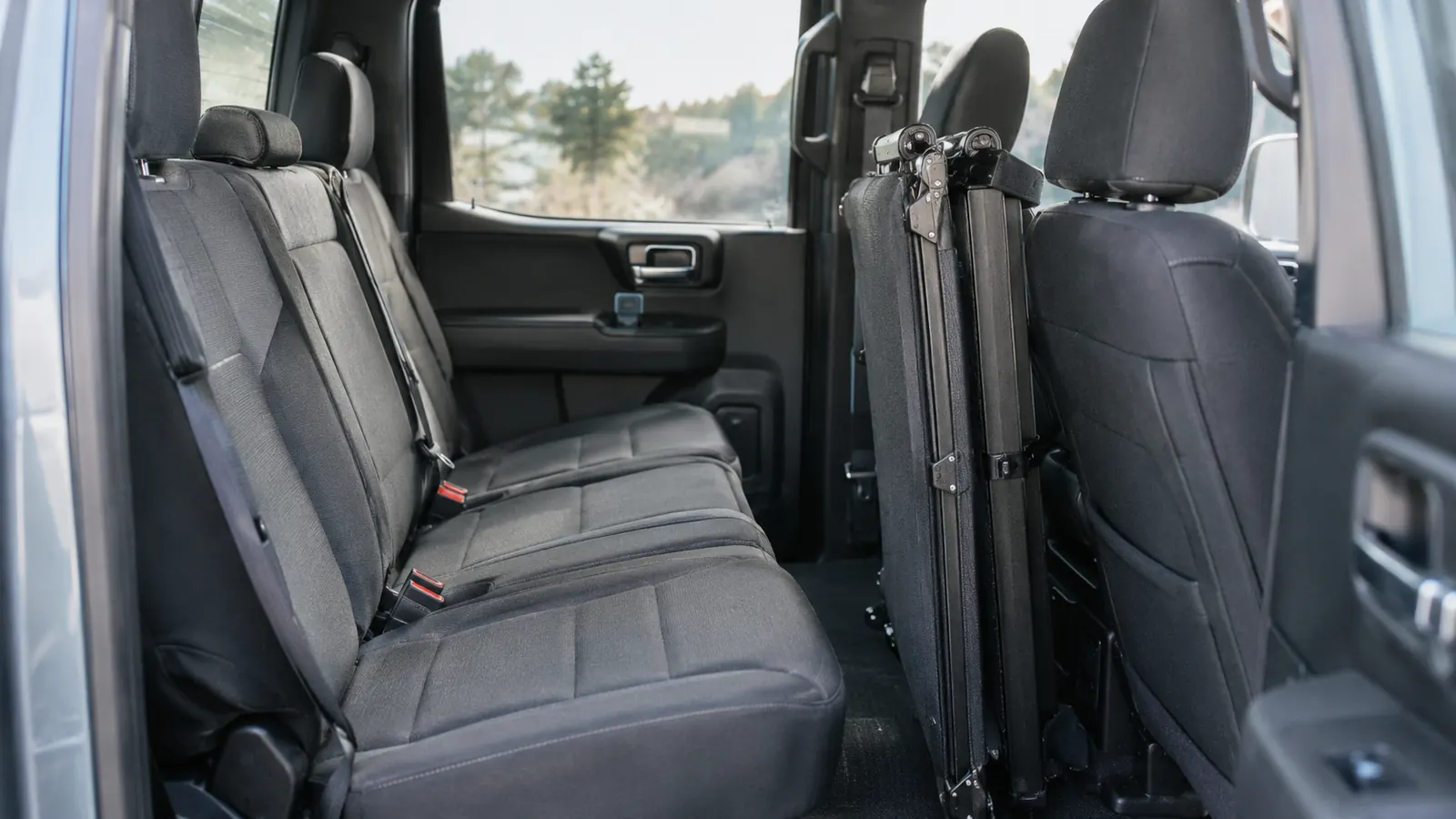 A folded dog ramp stored upright between the rear seat and the rear door inside a pickup truck cab